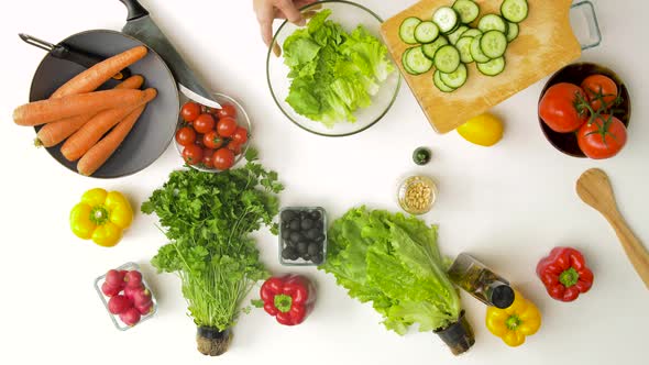 Young Woman Adding Cucumber To Salad at Home