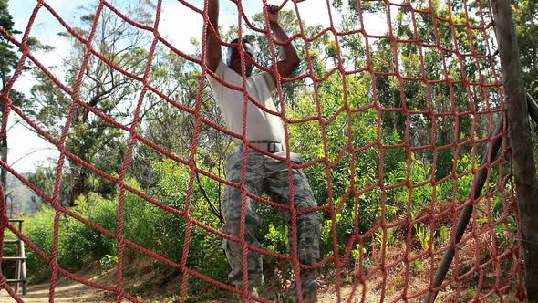 Military soldier climbing rope during obstacle course