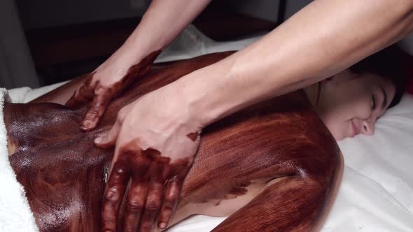 Closeup of Masseur Doing Massage with Chocolate Scrub