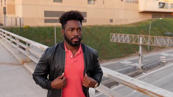 African-American man walks across a bridge over a freeway