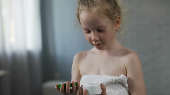 Pretty Female Kid Opening Cream Tube and Preparing for Daily Beauty Procedures