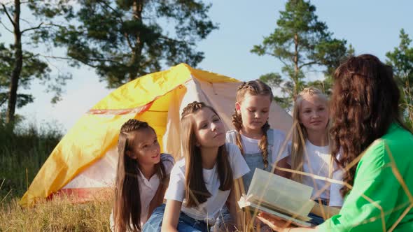 A Young Teacher Reads a Book to Girls in a Summer Camp Through the Work of an Educator