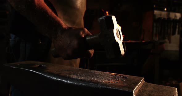 Mid-section of blacksmith walking with hammer