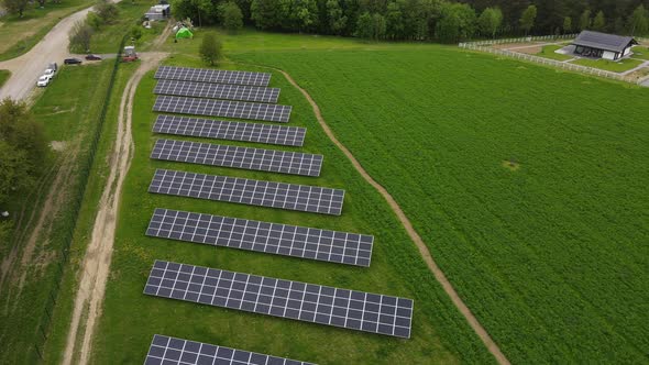 A new solar farm on a green field near a private house. Blue solar panels getting clean energy