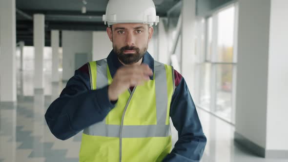 Slow Motion Portrait of Young Man Putting on Helmet and Crossing Arms Standing Inside Industrial