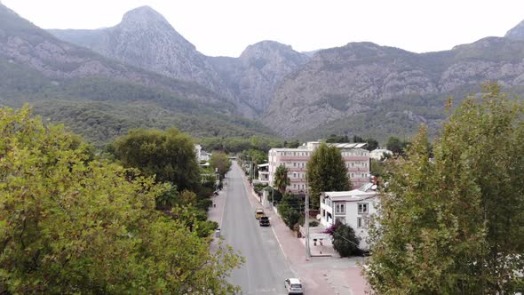 Aerial View of a Mountain Town with Beautiful Cottages Surrounded By Palm Trees and a Bus Parking on