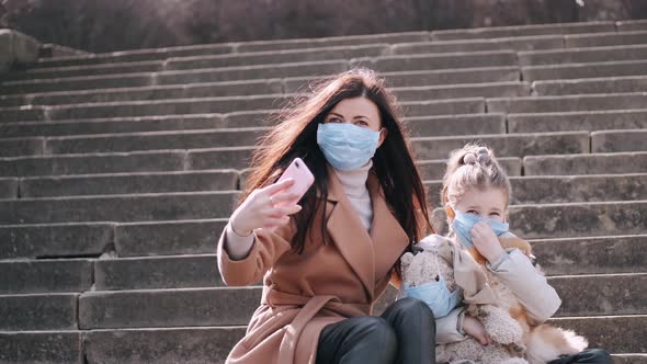 Mother and Daughter in Masks Are Taking Selfies on Stairs