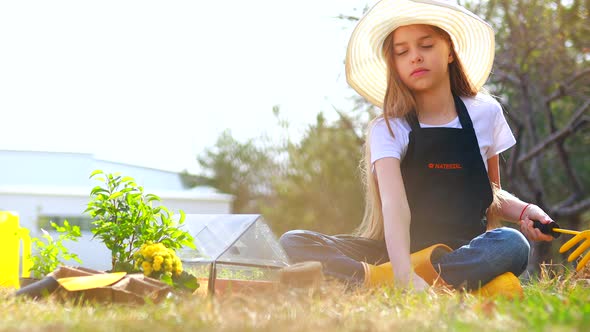 Beautiful Teen Age Girl in Black Apron and Yellow Rubber Shoes in Garden Nature and Care