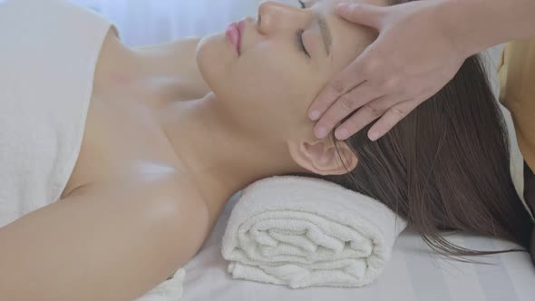 An young Asian woman lying down on a massage table in a spa at the resort during holiday.