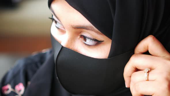 Side View of Muslim Woman with Flu Mask Looking Through Window