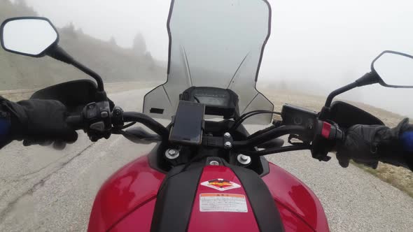 POV Biker on Motorcycle Rides on High Mountain Pass in Cloudy Weather with Fog