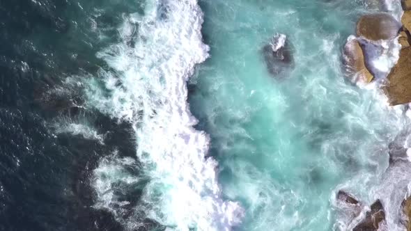 Top down bird eye view of strong and danger ocean waves crashing on to the rocks.