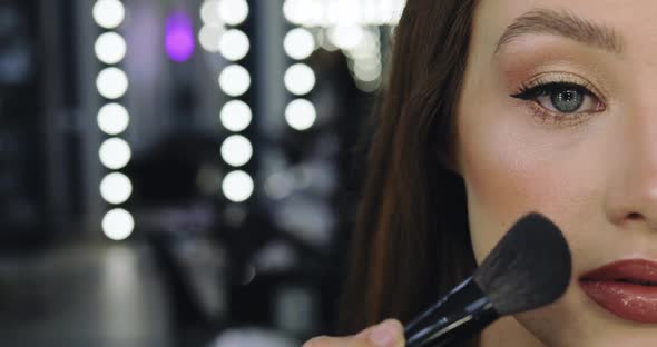 Closeup of Girl with Perfect Nude Makeup and Makeup Artist