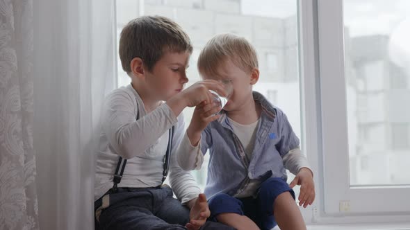Relationship of Children, a Caring Older Brother Gives His Little Sib Clear Glass with Cold Pure