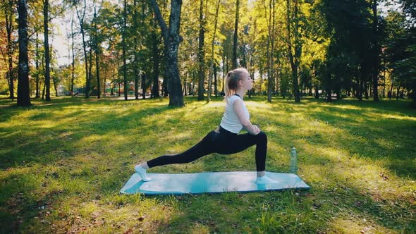 Focused purposeful girl sitting on the floor, blue mat, stretching her arms