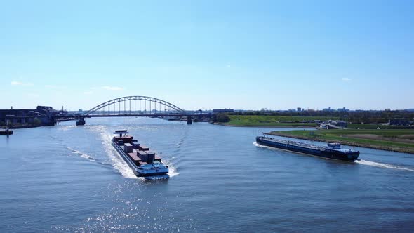 Shipping Inland Vessels Cruising At Noord River With Arch Bridge In The Distance At Hendrik-Ido-Amba