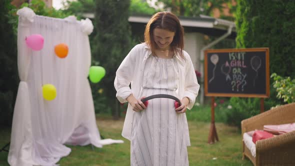 Smiling Pregnant Woman Holding Headphones on Belly Dancing in Slow Motion on Backyard