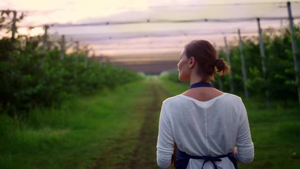 Farmer Woman Walking Inspecting Crop Produce in Summer Orchard Plantation House