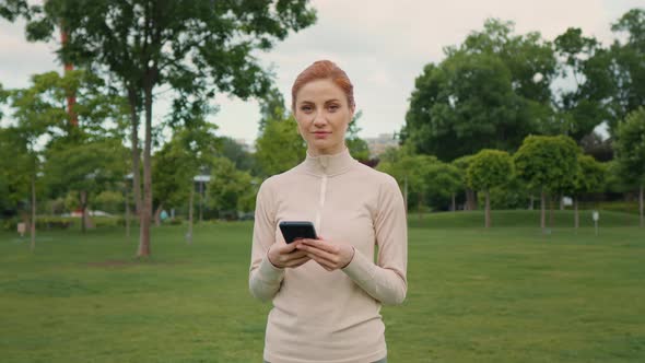 Female taking break from jogging and using smartphone