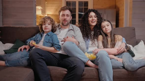 Family Watching a Movie Together at Home Hugging Eating Crisps and Laughing