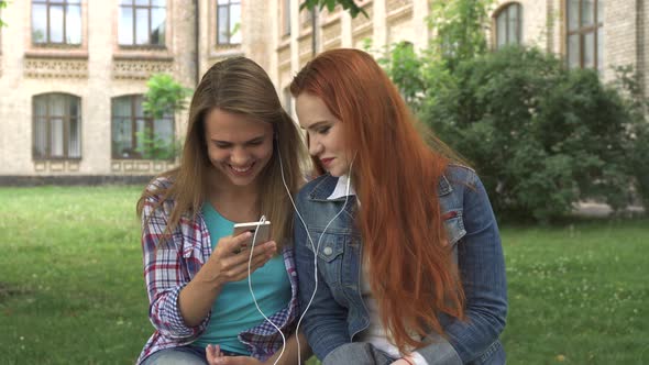 Female Students Listen To Music on Smartphone on Campus