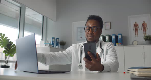 African Md Wearing White Coat and Stethoscope Communication with Patient Via Video Chat on Phone