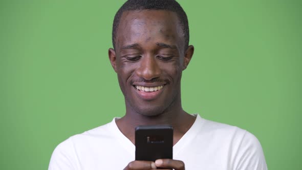 Young African Man Using Phone Against Green Background