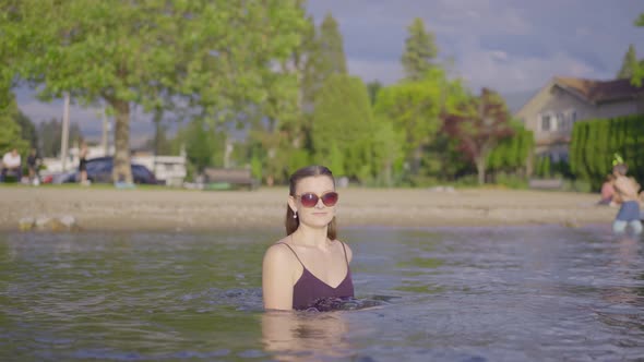 Young attractive girl in sunglasses playing in the water