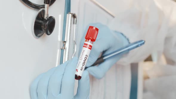 Vertical Footage Doctors Hand Holding Tube with Positive Blood Test for COVID-19