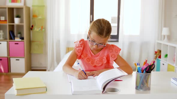 Student Girl with Book Writing To Notebook at Home