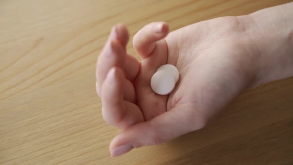 Two White Pills Fall on a Woman Palm From Bottle of Pills