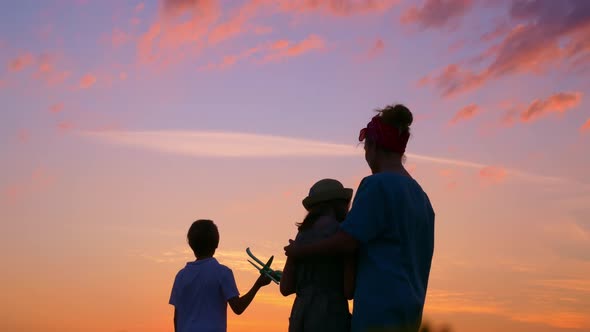 A Happy Family Meets the Sunset Together a Mother with Children Stands in a Field in the Rays of the