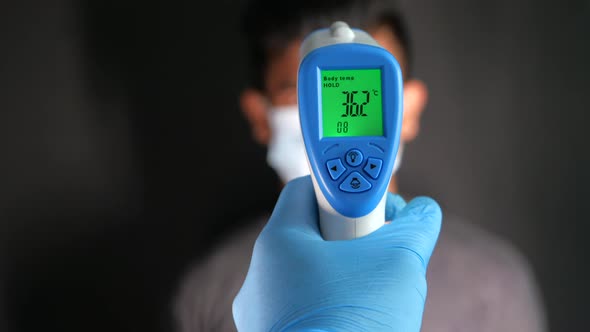 Hand Holding Infrared Thermometer To Measuring Temperature.