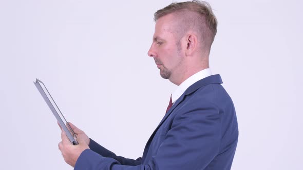 Profile View of Blonde Businessman with Digital Tablet Being Taken Away