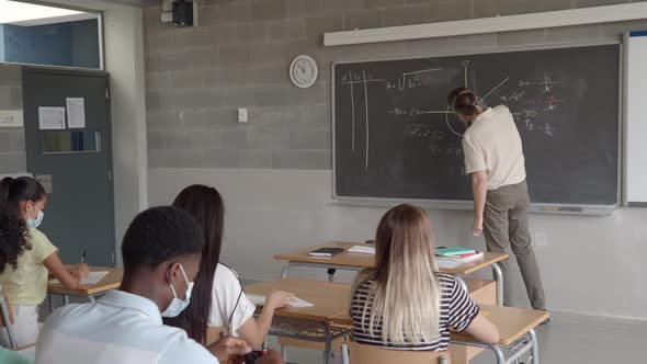 Male Teacher with Medical Mask in a Classroom Explaining Mathematics in a Class