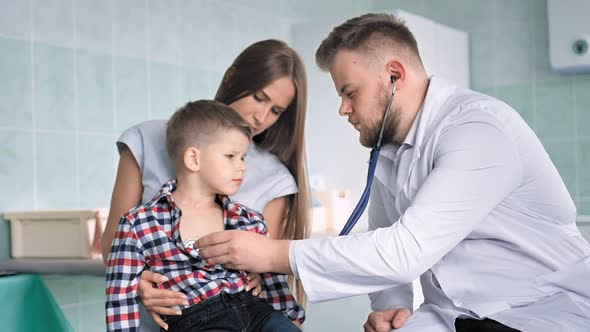 Physician in White Lab Coat Examines Rib Cage of Sick Child Using Stethoscope