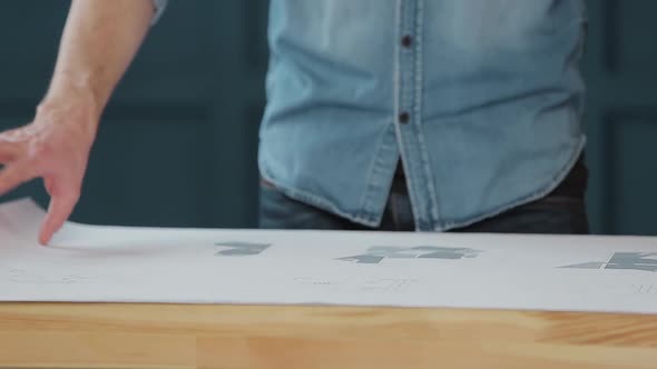 Close Up Shot of Young Man Hands Engineer Opening the Paper and Checking the Construction Drawings