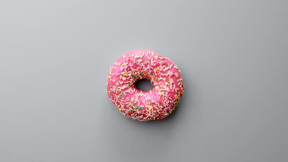 Top View Slowly Rotating Appetizing Fresh Ring Donut with Pink Icing Isolated