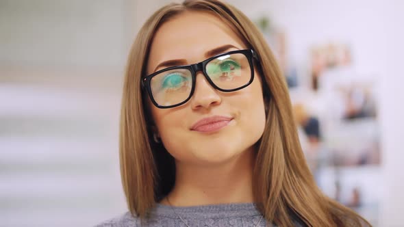 Closeup Portrait of Woman Smiles for Camera Puts on Glasses