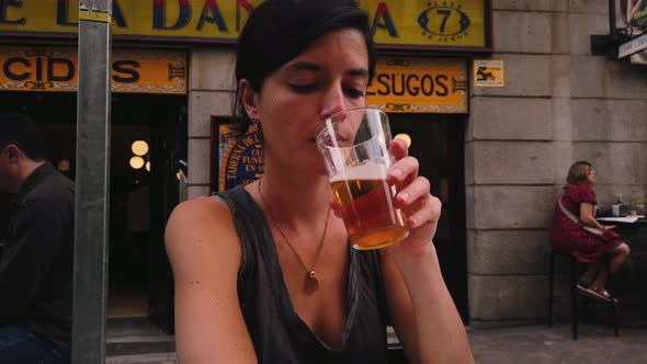 Beautiful Caucasian woman drinks beer in a bar in Madrid (Spain). Spanish girl sitting on a terrace