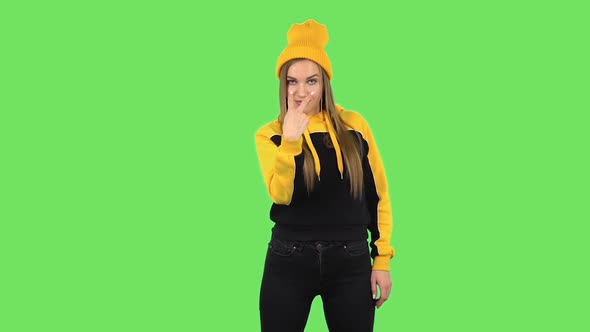 Modern Girl in Yellow Hat Is Threatening, Showing Gestures While Looking at the Camera. Green Screen