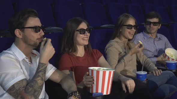 Two Couples Sit in the Cinema and Eat Popcorn