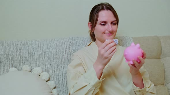 Woman musician with piggy bank at home on sofa in living room