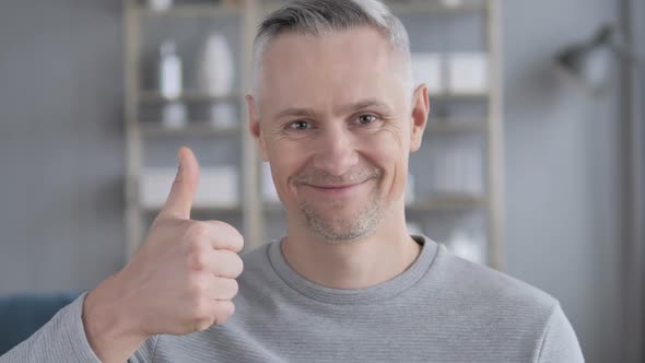 Thumbs Up By Gray Hair Man at Work Looking at Camera