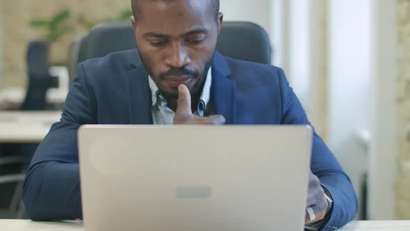 Concentrated Handsome African American Businessman Working Online Using Laptop. Portrait of