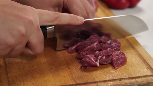 Closeup of a Woman Slicing Red Meat on a Kitchen Board