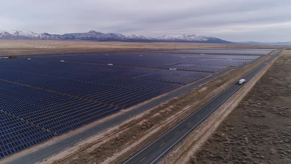 Trucks on the highway next to solar farm looking towards snow capped mountains