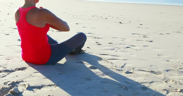 Senior woman doing yoga on the beach