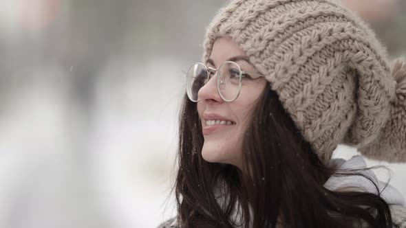 Charming Young Woman with Glasses and Nice Knitted Hat Is Walking at Winter Closeup Portrait