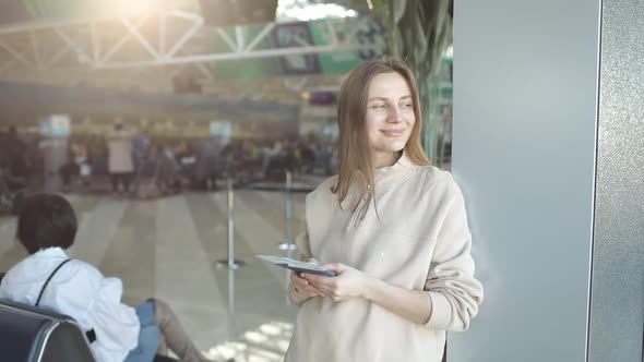 Happy cheerful young woman standing in front of camera, getting visa, holding tickets passport 